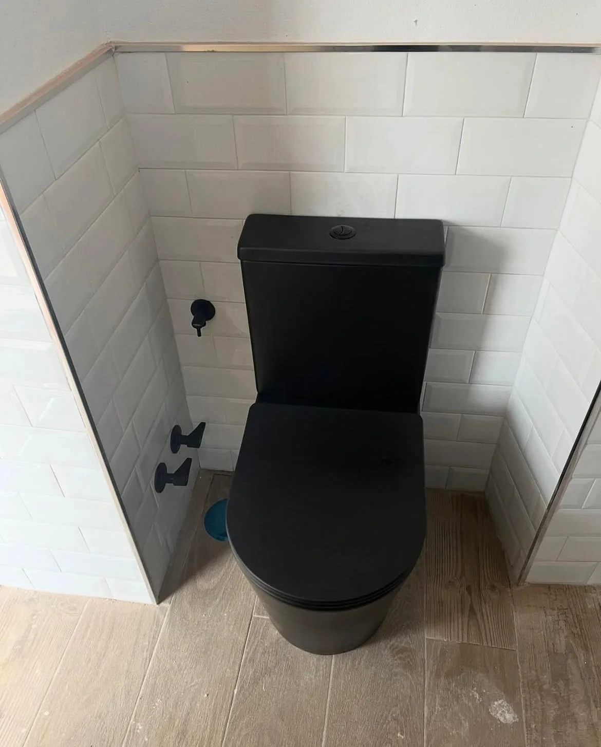 Inodoro negro instalado en un baño reformado